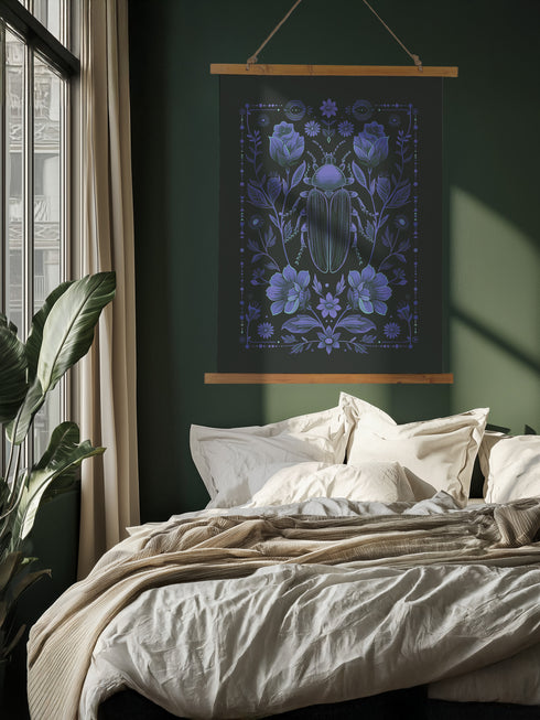 A symmetrical dark wall tapestry featuring a large iridescent blue beetle centered among intricate floral motifs and botanical elements on a black background, suspended from a wooden dowel with twine.